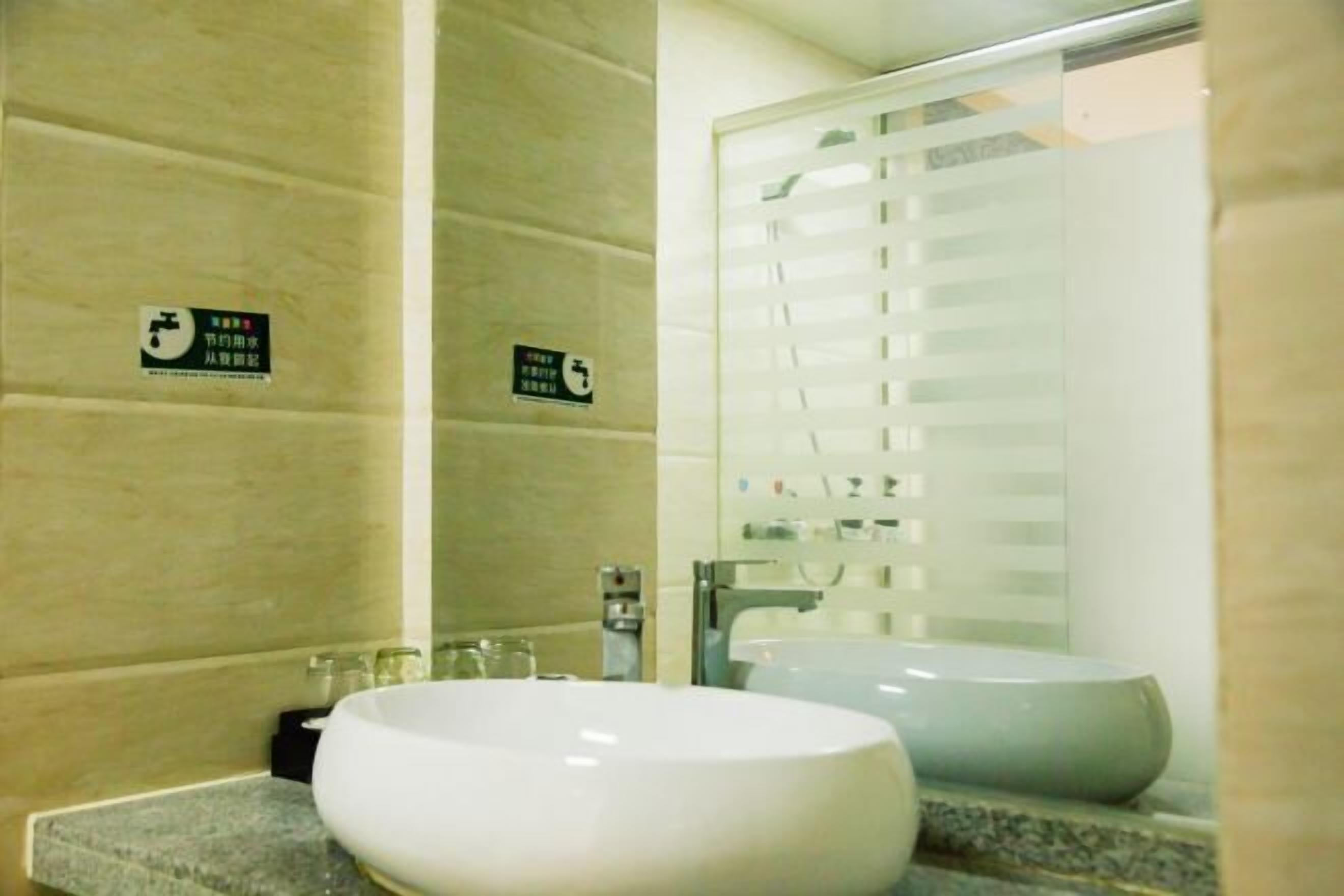 A bathroom with a large white sink, a mirror, and a shower with frosted glass doors.