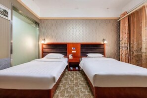 Hotellihuone, jossa on kaksi erillistä sänkyä, puinen pääty, kuvioitu matto ja seinä, jossa on pyöreitä kuvioita.