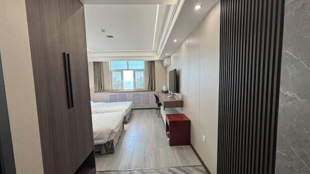 A hotel room with a bed, a desk, a TV, and a window. - Longhua Hotel (West Ring Road (Karamay)