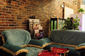 A room with a brick wall, two sofas, a small table, and a plant. - Longhua Hotel (West Ring Road (Karamay)