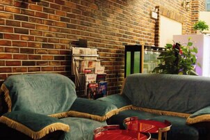 A room with a brick wall, two sofas, a small table, and a plant.