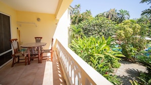 A balcony with a table and chairs, a view of a pool, and lush greenery. - Room-2br Caribbean Condo In Cabarete Cen (Sosúa)