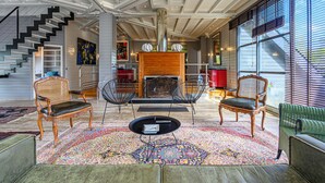 A spacious living area with a staircase, modern and traditional furniture, a fireplace, and large windows.