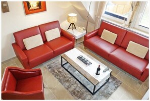 Ein Wohnzimmer mit zwei roten Sofas, einem Couchtisch und einer Lampe.