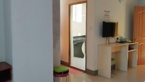 Una habitación con escritorio, una silla, un televisor y una puerta que da a otra habitación.