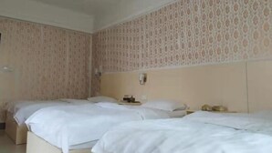 Habitación de hotel con dos camas, cabecero, mesita de noche y teléfono instalado en la pared.