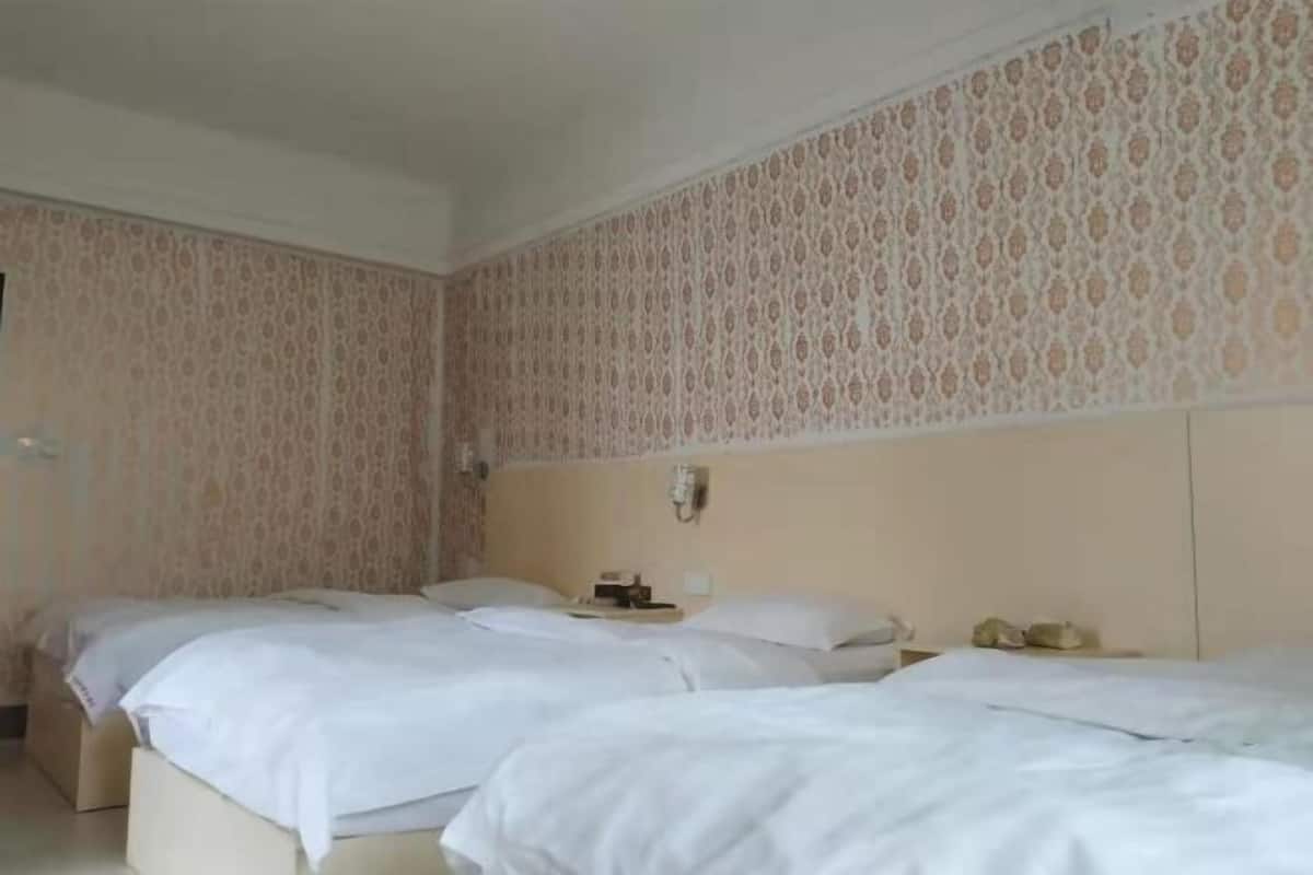 Hotellihuone, jossa on kaksi sänkyä, sängynpääty, yöpöytä ja seinään asennettu puhelin.