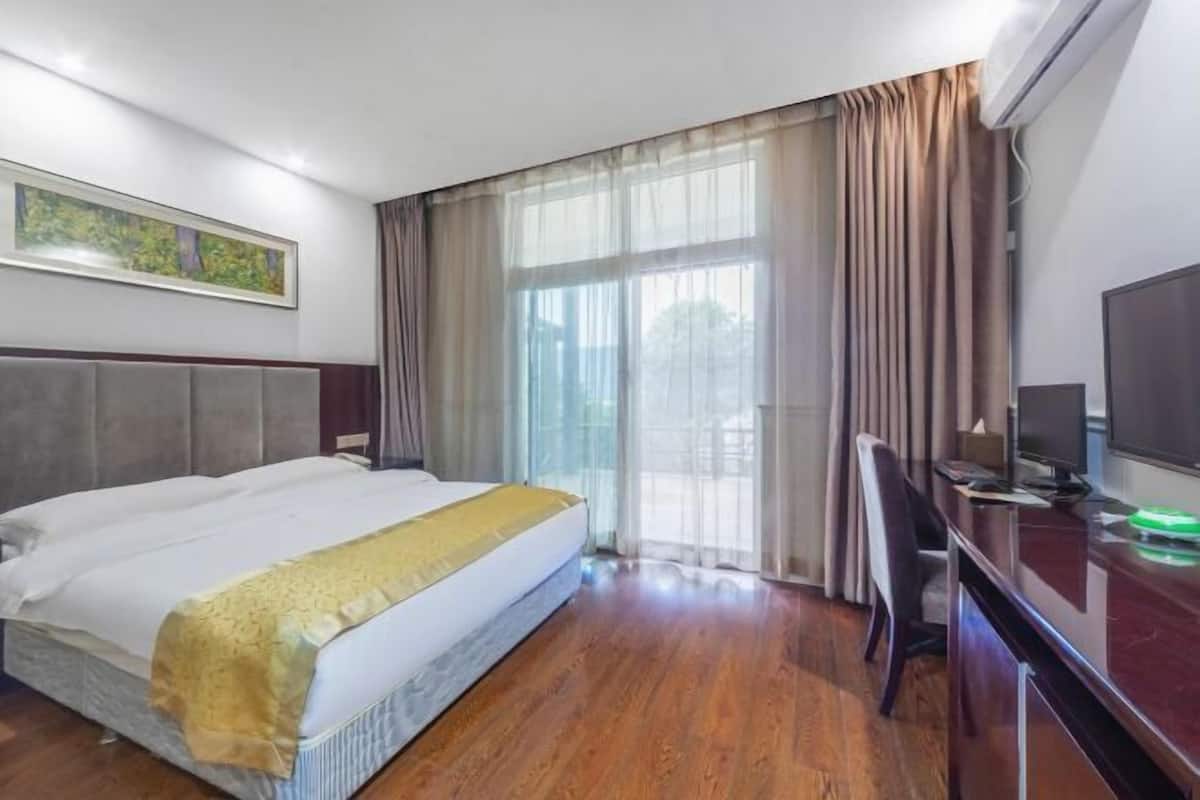 A hotel room with a bed, a desk, a television, and a window with curtains.