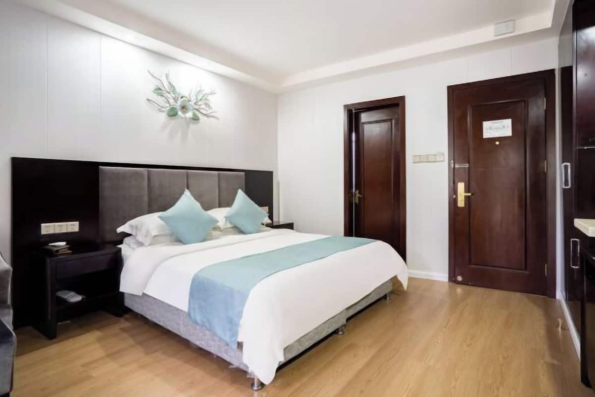 A hotel room with a bed, a nightstand, a wall-mounted light fixture, and two doors.
