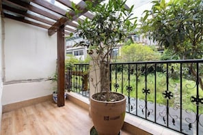 Un balcon agrémenté d’un pot de fleurs, d’une pergola en bois et d’une rambarde en métal.