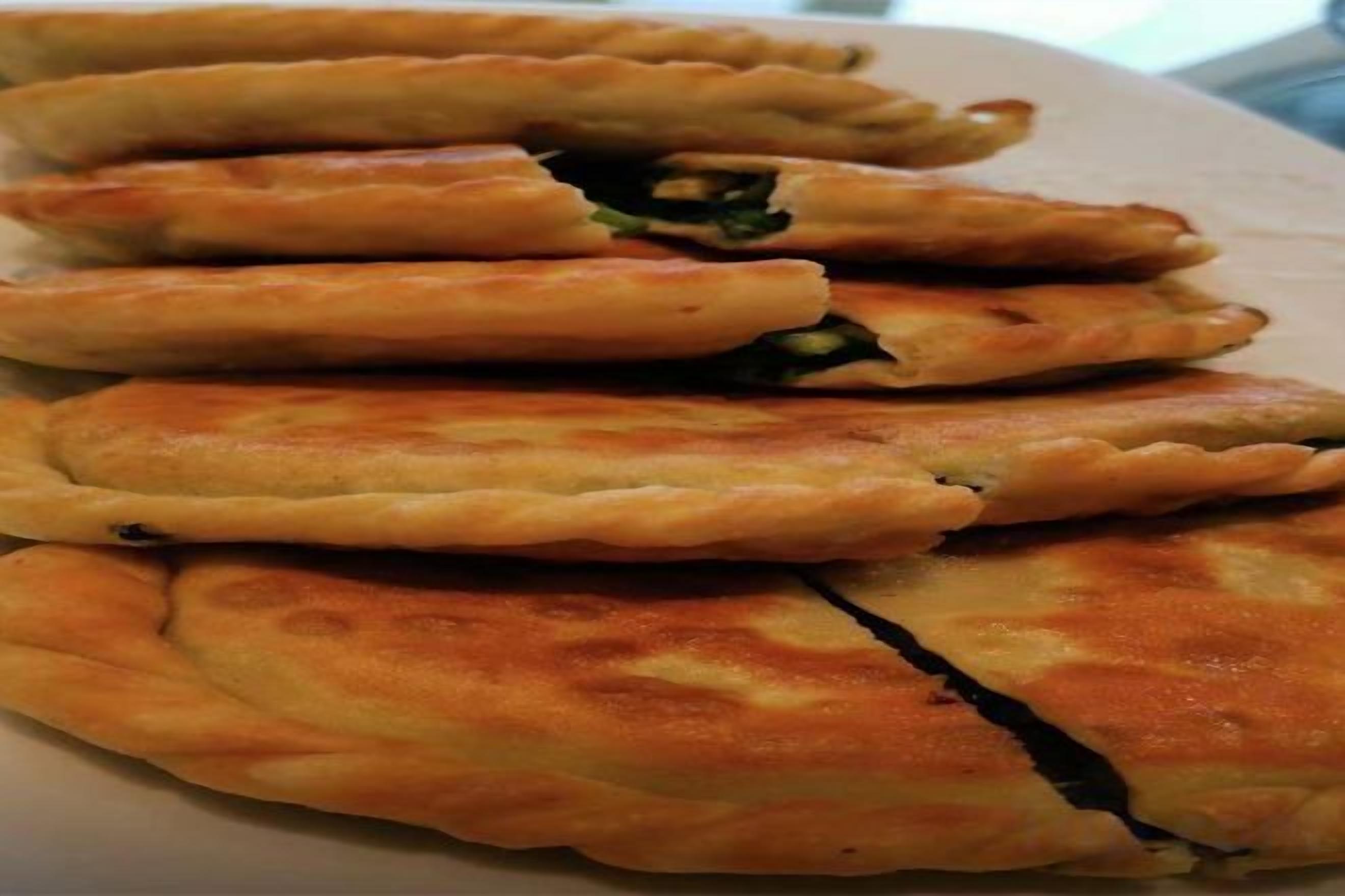 A stack of golden-brown pastries with a visible filling, placed on a white surface.