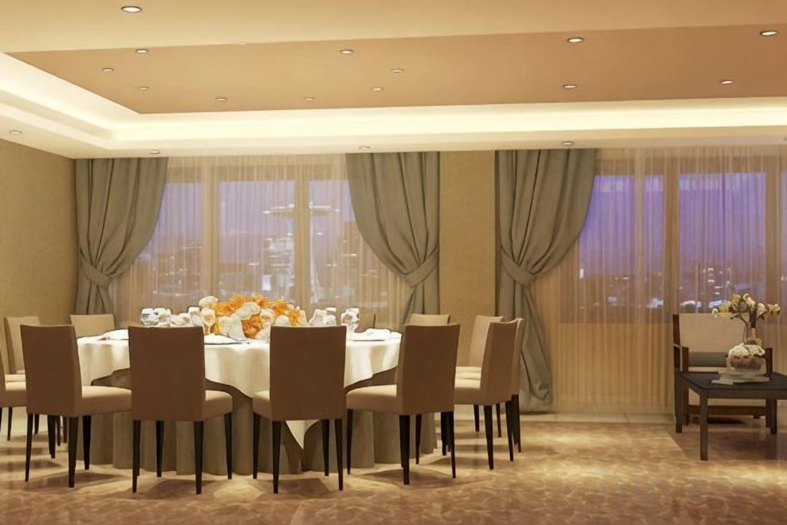 A dining area with a round table, chairs, and a city view through large windows.