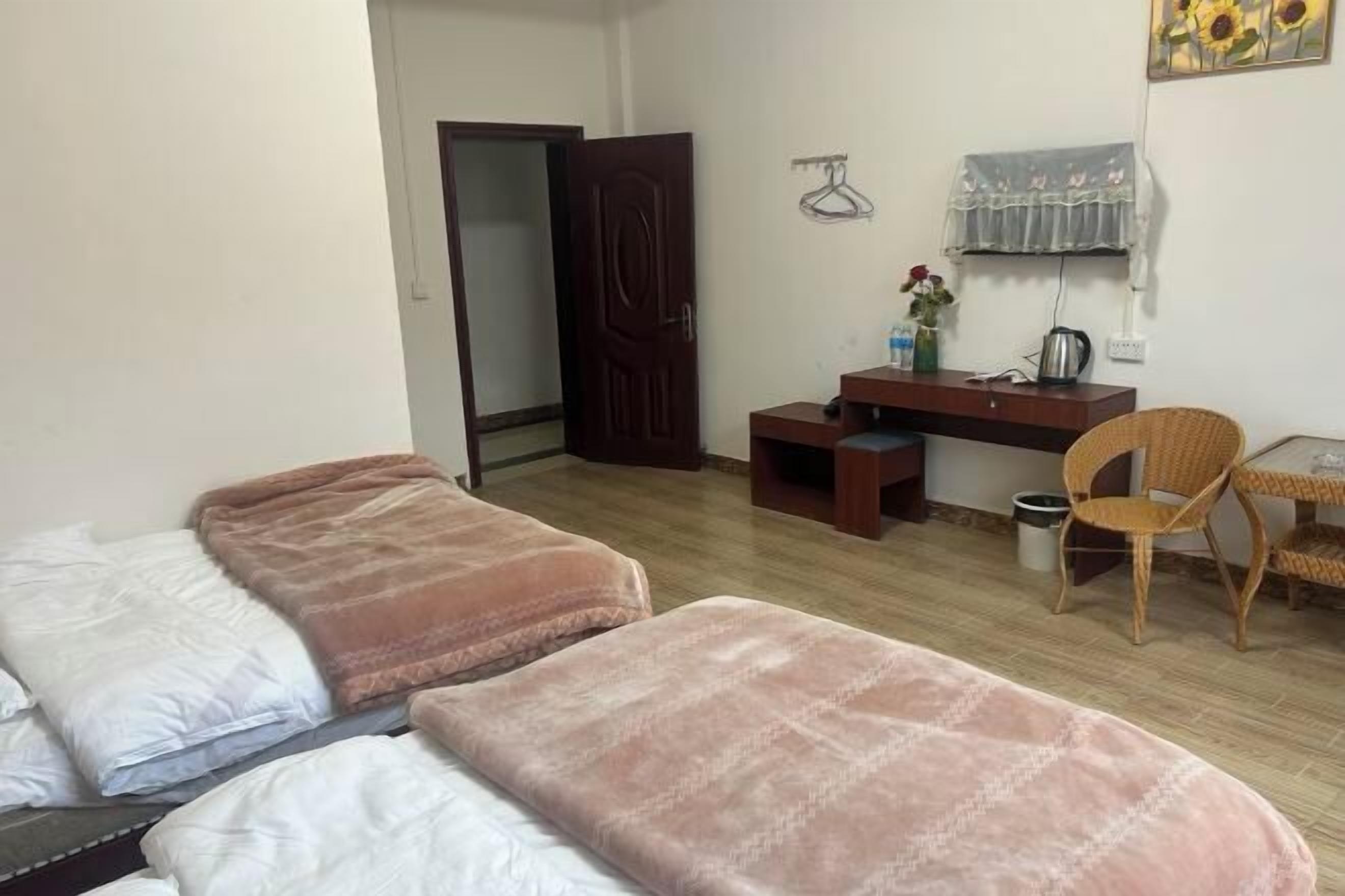 A room with two beds, a desk, a chair, and a wardrobe.