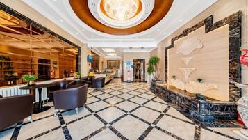 A hotel lobby with a check-in counter, seating area, and a decorative wall.