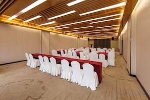 Un salón de conferencias con una larga mesa y sillas, paneles de techo de madera y suelo alfombrado.