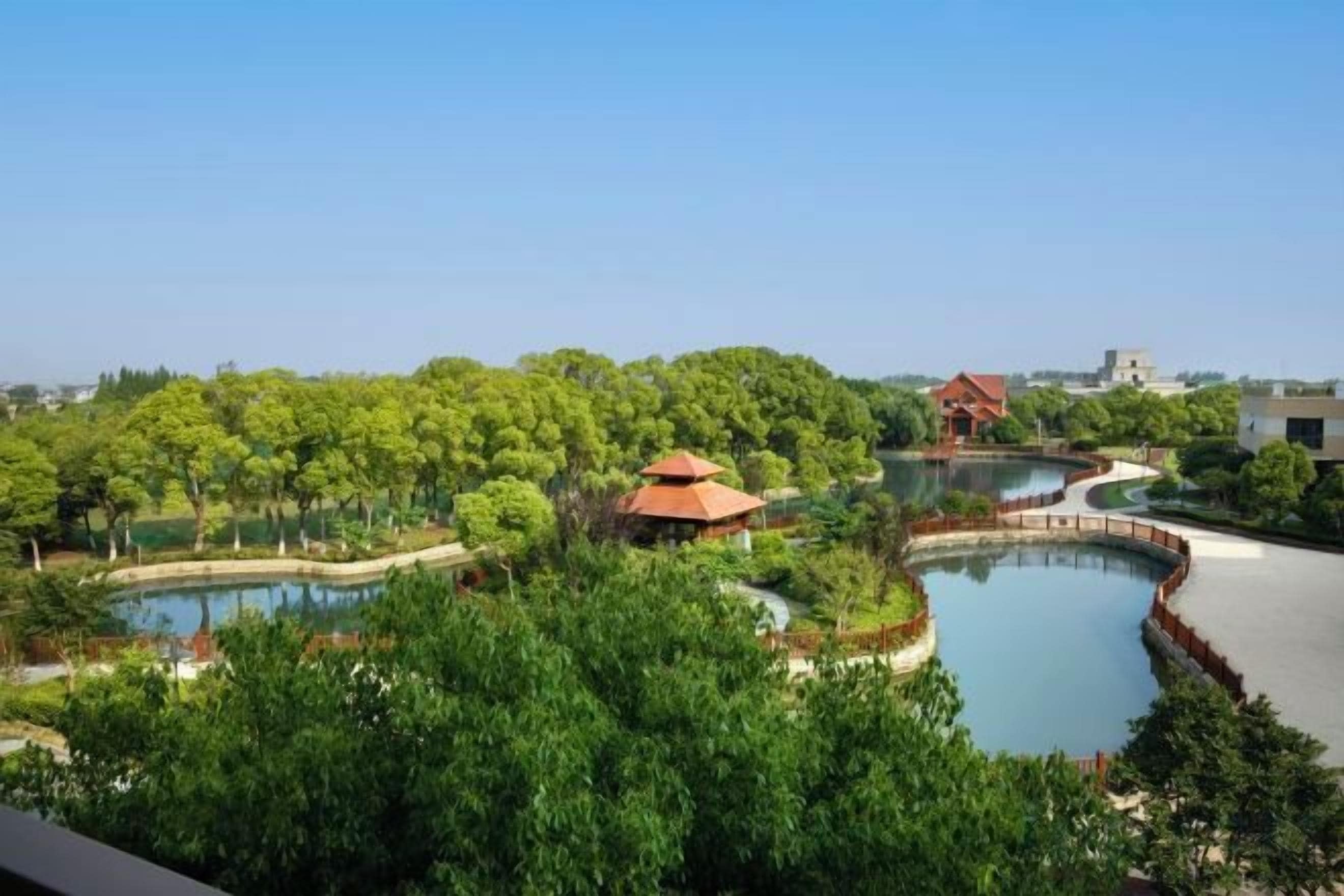 A landscaped area with a pond, trees, and a building with a red roof.