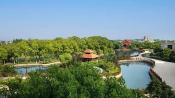 A landscaped area with a pond, trees, and a building with a red roof.