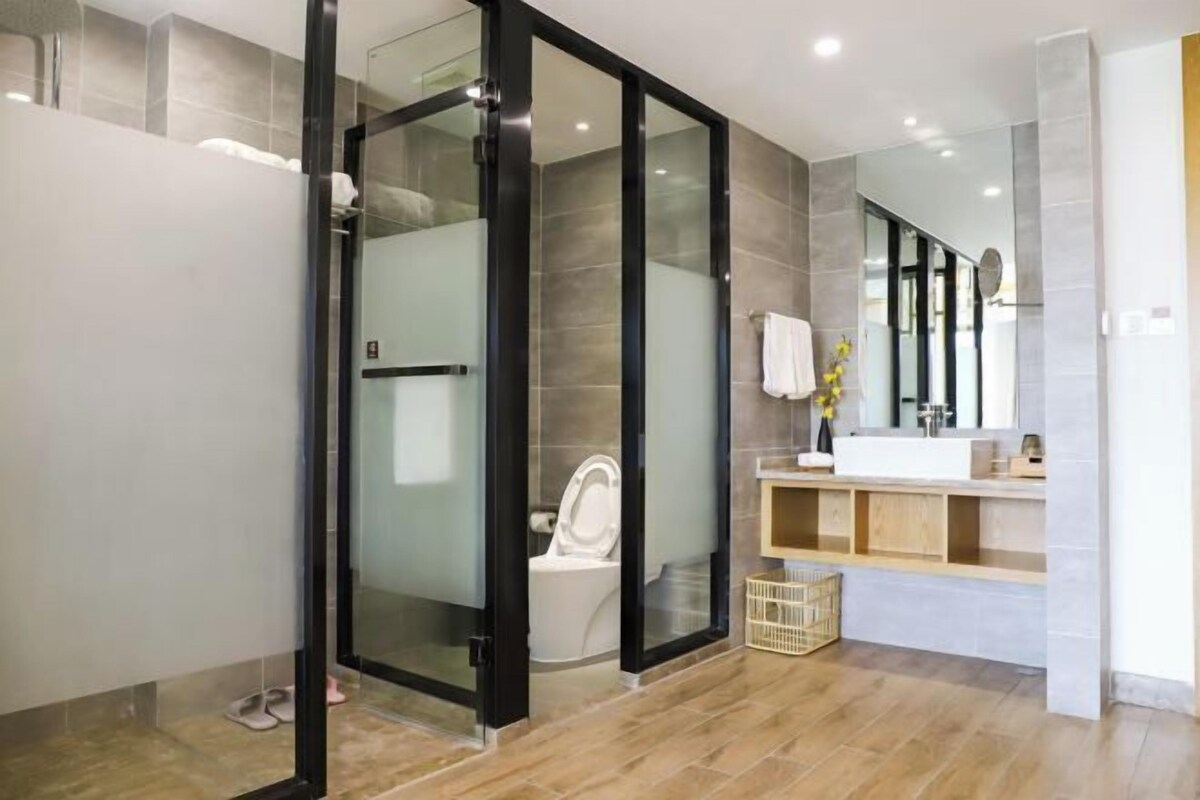 Une salle de bain moderne avec une douche à parois de verre, des toilettes et un meuble-lavabo avec un miroir.