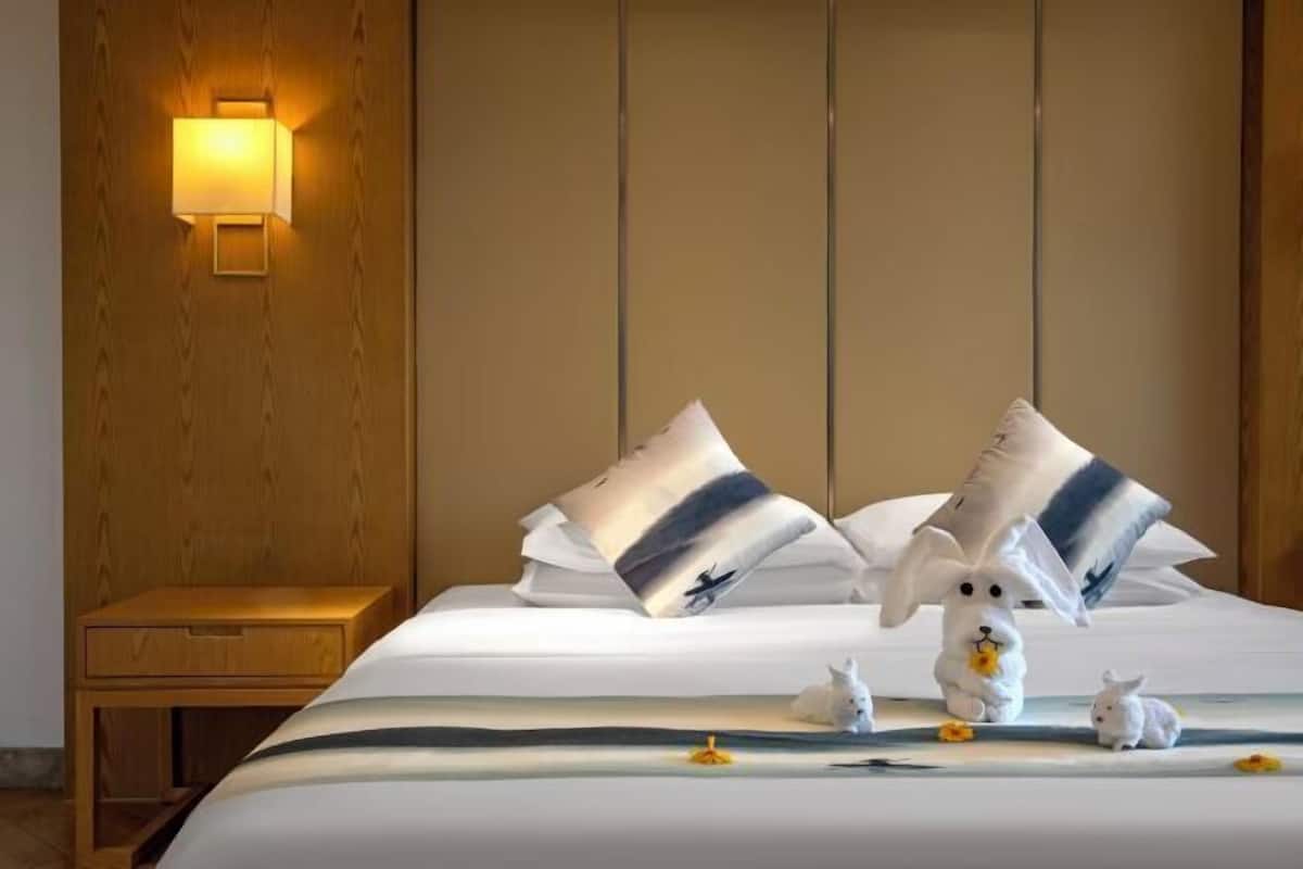 Una habitación de hotel con cabecera de madera, una mesita de noche y almohadas decorativas.