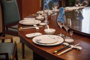A dining table set with plates, bowls, chopsticks, and wine glasses, indicating a formal dining arrangement.
