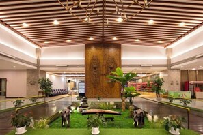 Un hall d’entrée spacieux avec une colonne centrale, un espace salon et des plantes d’intérieur.
