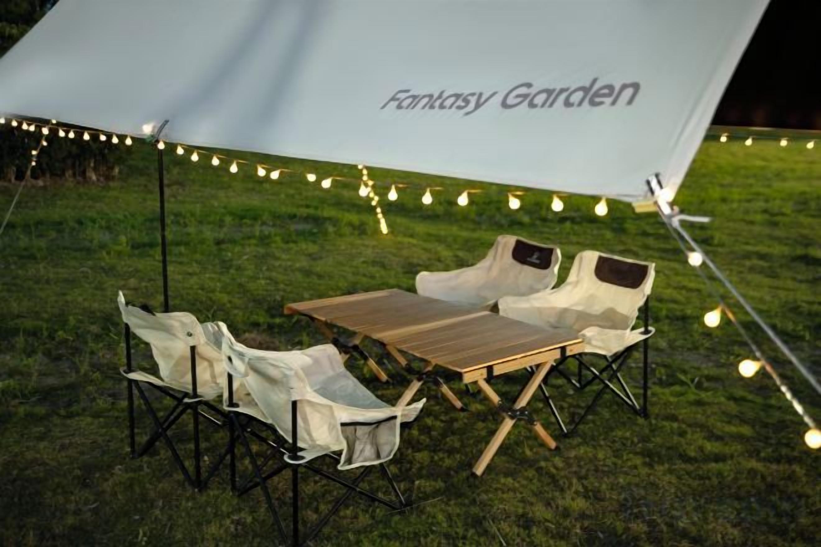 An outdoor seating area with a table and chairs under a canopy with 'Fantasy Garden' written on it.