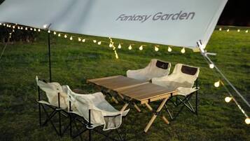 An outdoor seating area with a table and chairs under a canopy with 'Fantasy Garden' written on it.