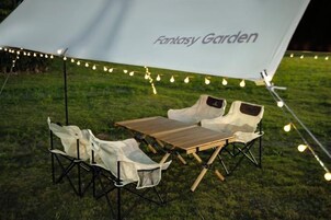Un área de estar al aire libre con una mesa y sillas bajo un toldo que dice 'Fantasy Garden'.