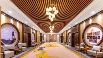 Un vestíbulo de hotel con alfombra central, zonas de estar y techo de madera.