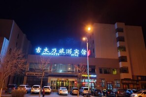 Un hotel con un letrero llamativo, varios espacios de estacionamiento y una farola.