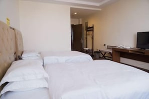 A hotel room with two beds, a desk, a television, and a mirror.