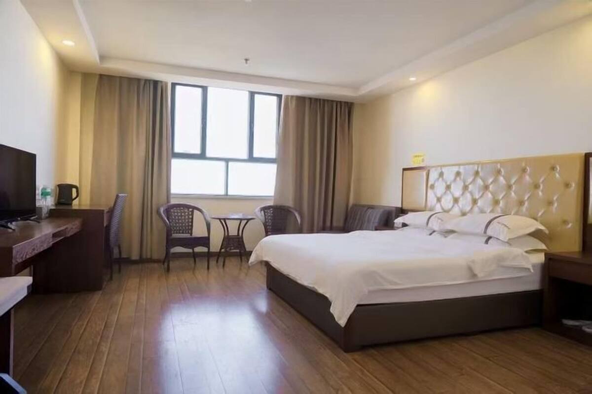 Een hotelkamer met een bed, een bureau, een stoel, een bijzettafeltje en een televisie.