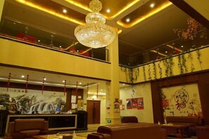 Un hall de hotel con una recepción, zona de estar y un candelabro.
