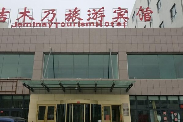 A hotel entrance with a glass canopy and a sign in both Chinese and English.