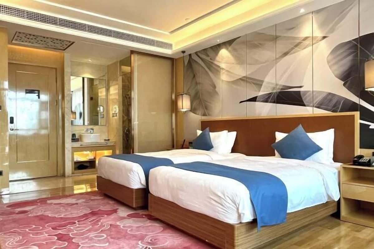 Une chambre d’hôtel avec deux lits, une salle de bain et une grande fresque murale abstraite.