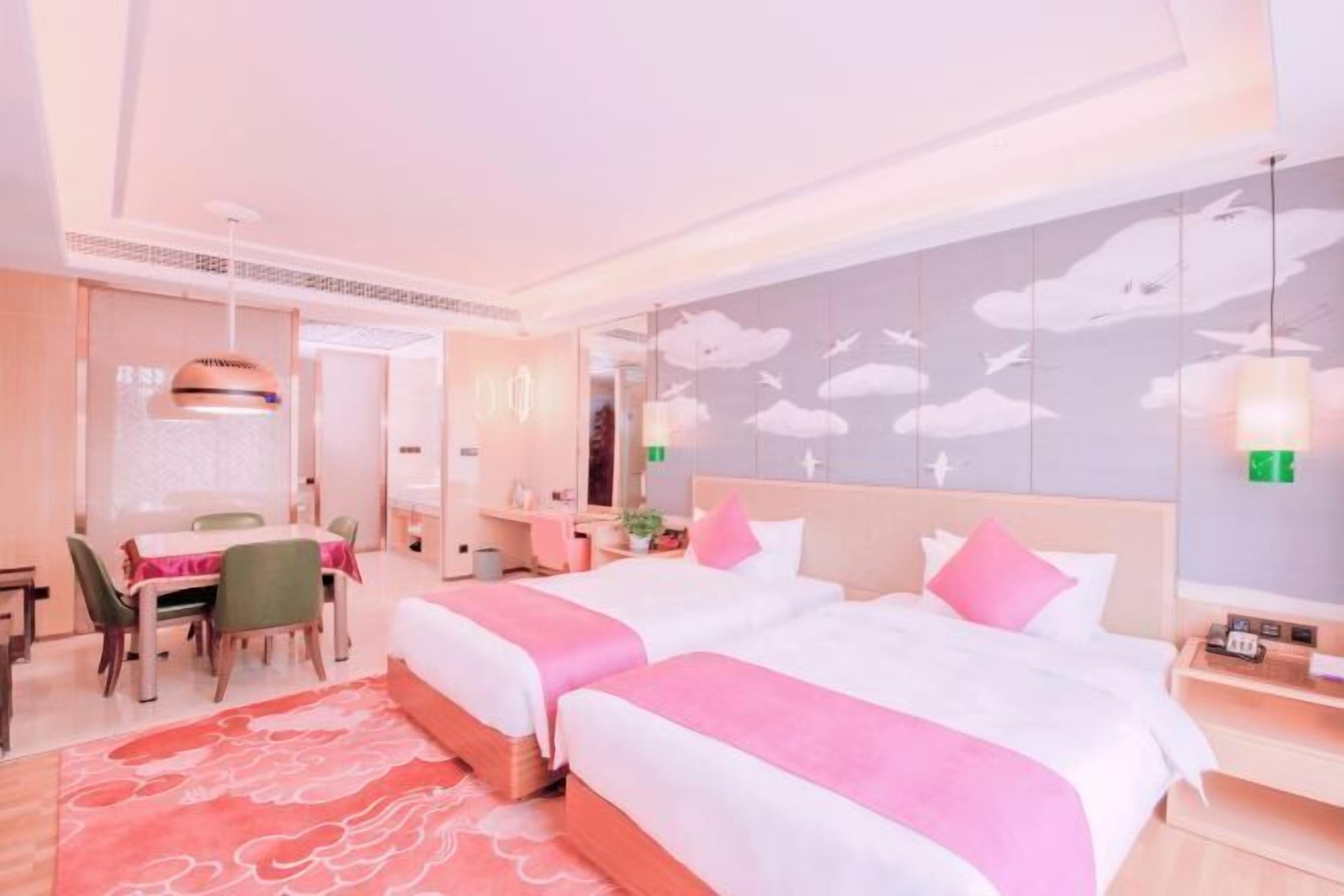 Ein Hotelzimmer mit zwei Betten, einem Essbereich und einer Wand mit Wolkenmustern.