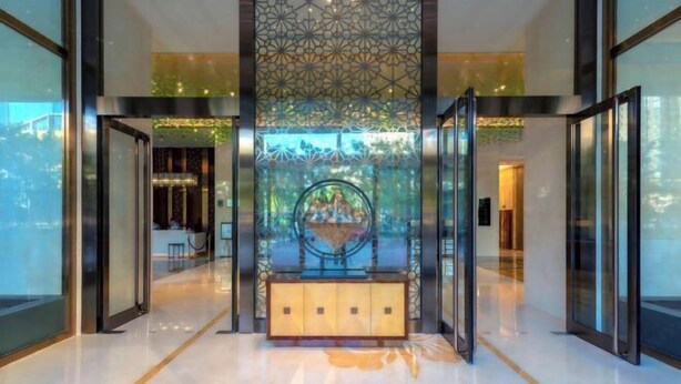 Una hall d'albergo moderna con un elemento decorativo centrale, porte in vetro e un pavimento lucidato.