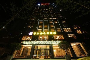Un hotel de varios pisos con señalización iluminada y una entrada bien iluminada.