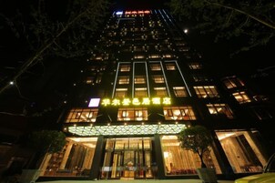 Un hotel de varios pisos con señalización iluminada y una entrada bien iluminada.