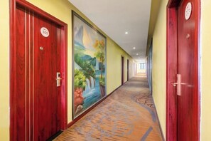 A hotel corridor with red doors, a mural, and a patterned carpet.
