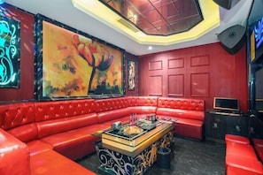 A red leather sofa, a table with decorative items, and a large abstract painting.