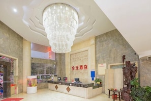 A hotel reception area with a chandelier, reception desk, and a sign with Chinese characters.