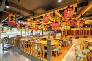 A restaurant with wooden tables and chairs, red lanterns, and a view of the street.