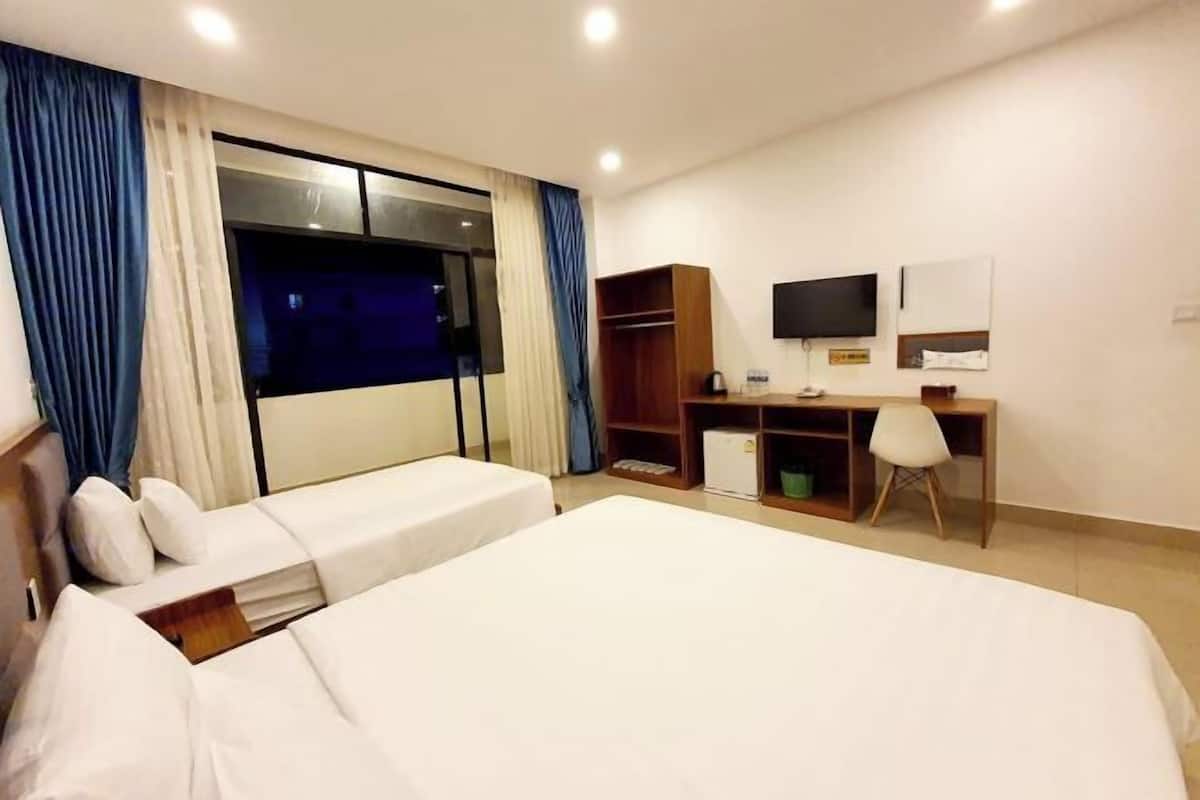 A hotel room with two beds, a desk, a chair, a TV, and a wardrobe.
