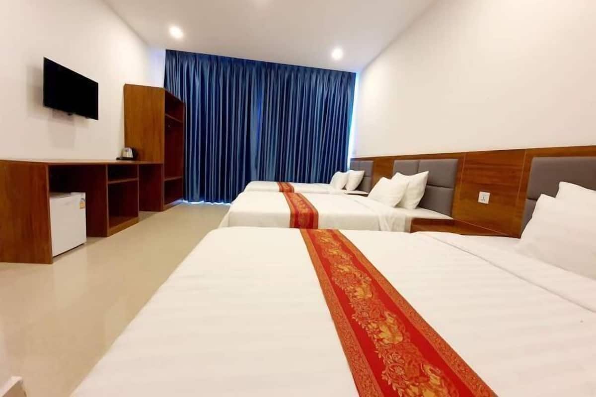 A hotel room with two beds, a TV, a desk, and a wardrobe.