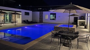 Ein Swimmingpool mit Whirlpool, Sitzgelegenheiten im Freien und einer Grillzone.