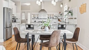 A modern kitchen with white cabinets, stainless steel appliances, and pendant lighting.