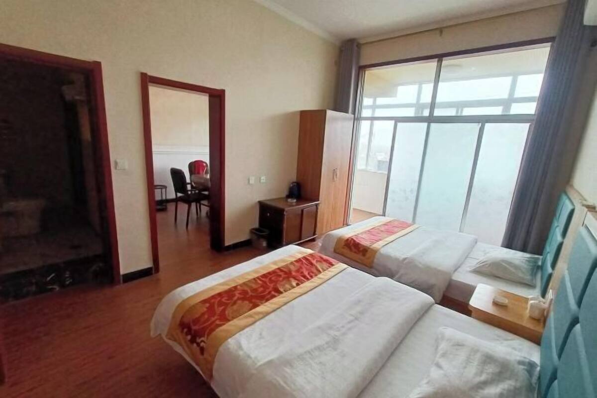 A hotel room with two beds, a desk, a chair, and a wardrobe.