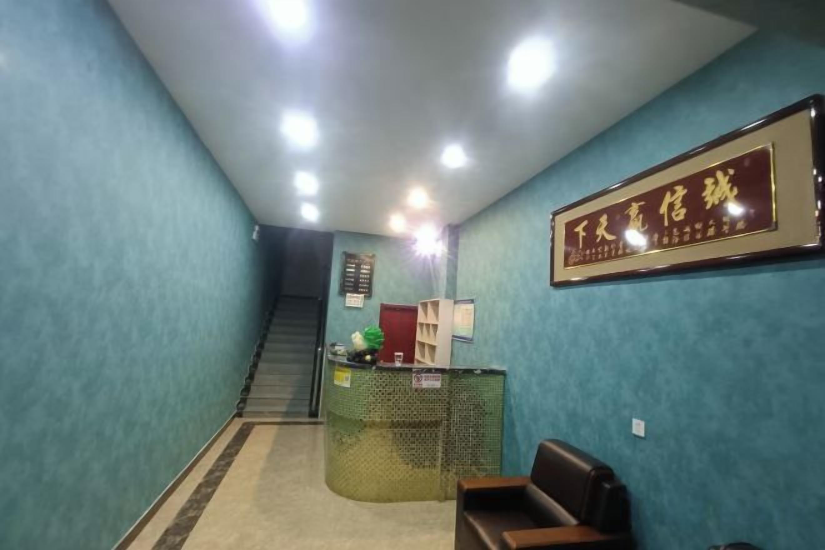 A reception area with a reception desk, a framed sign, a staircase, and a seating area.