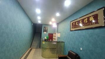 A reception area with a reception desk, a framed sign, a staircase, and a seating area.